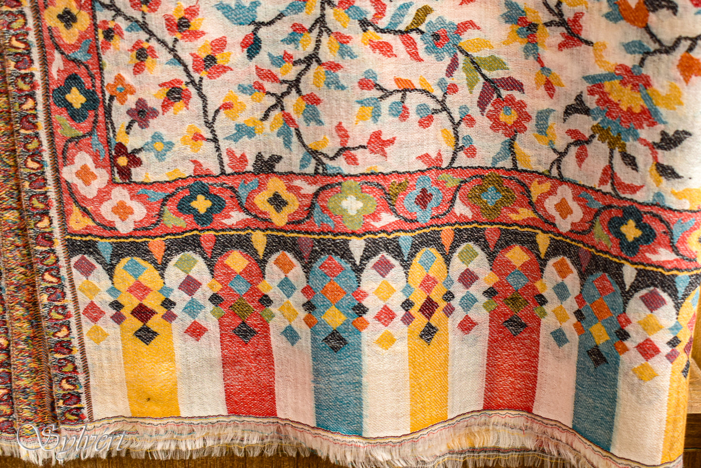 Close up textured shot of a draped and displayed white and red Visserella pashmina and cashmere blended stole with floral motifs from Sylvért's Vissera collection