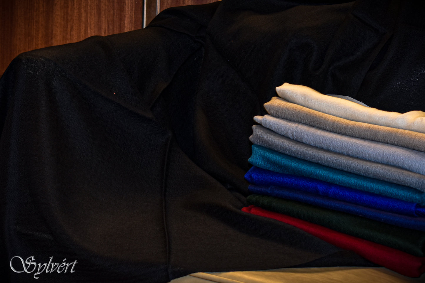 Product image of a folded stack of Rivesta cashmere stoles from Sylvért's Rivanor collection in white grey, light slate, blue royal blue, navy, green, red and black