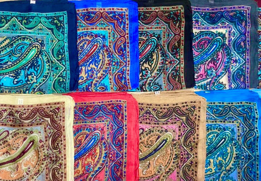 Colorful silk scarves with intricate paisley patterns arranged in two rows on display