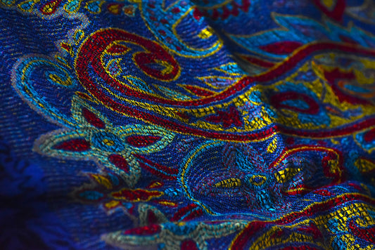 Close-up of vibrant blue fabric with intricate red, yellow, and turquoise paisley embroidery
