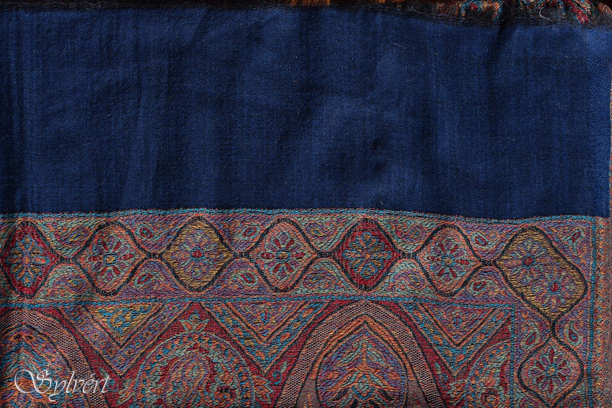 Blue textile fabric with intricate multicolor paisley border and floral embroidery pattern