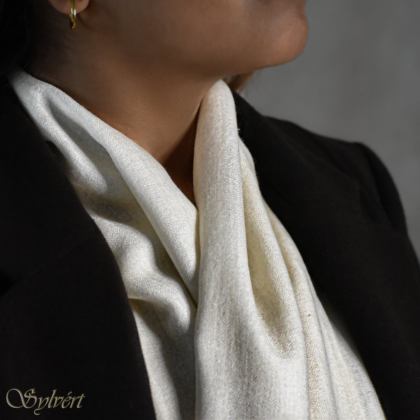 A styled showcase of a white Corvella Orien from Sylvért's Coronis Collection, worn snugly under a brown coat