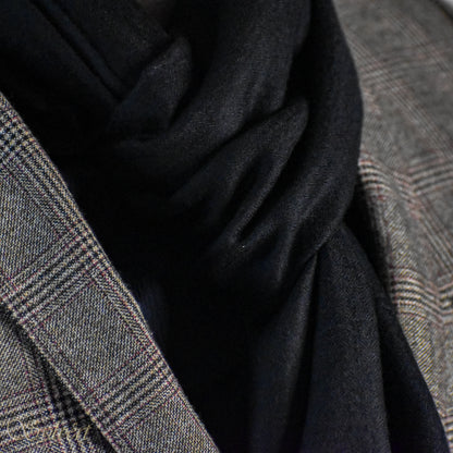 A styled showcase of a black Corvella Noctra from Sylvért's Coronis Collection, worn snugly under a grey plaid blazer