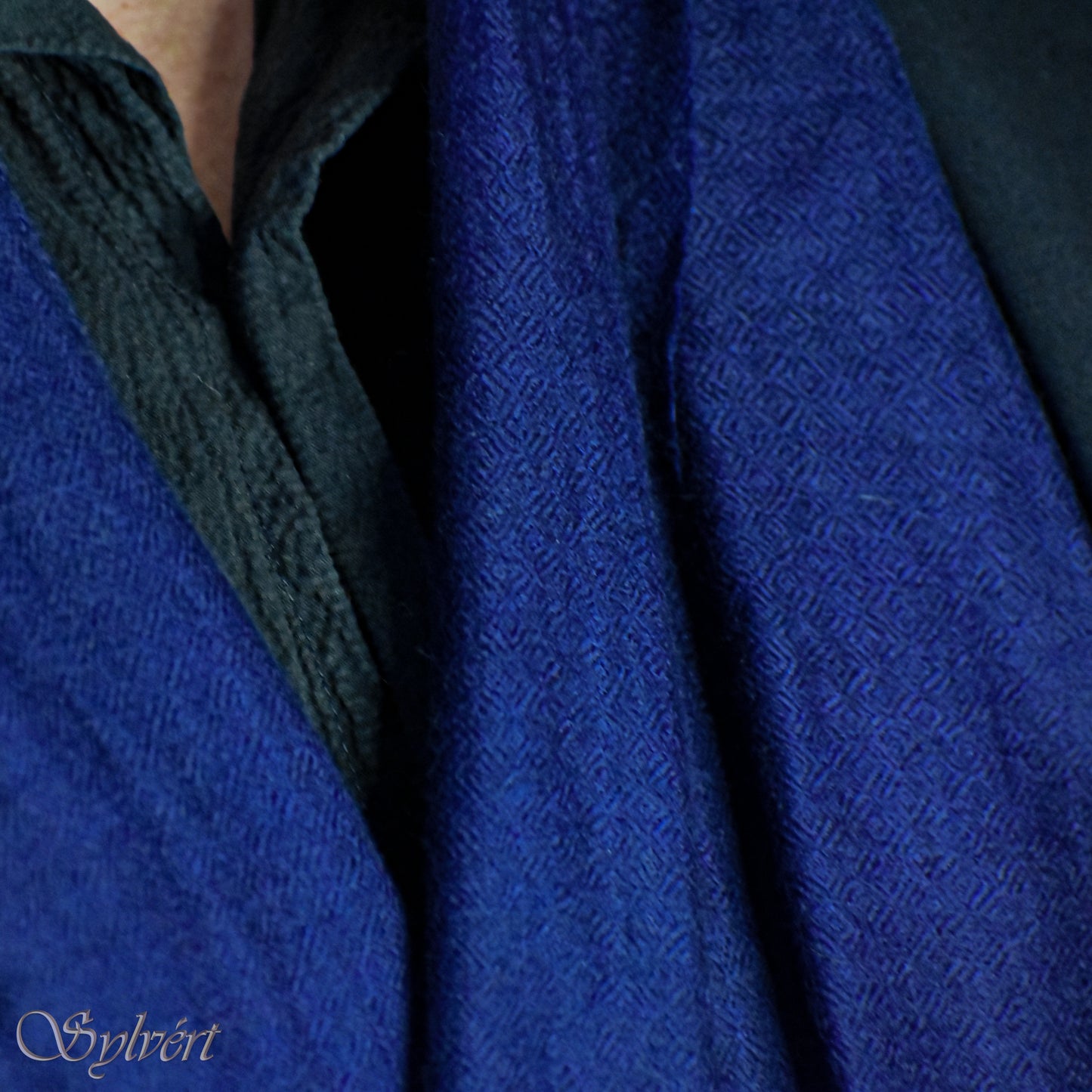 A styled showcase of a blue Corvella Norien from Sylvért's Coronis Collection, worn loosely under a blue jacket