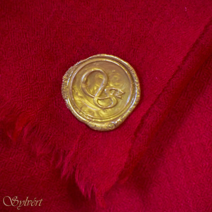 A red Corvella Sorell from Sylvért's Coronis collection, folded to show the diamond weave texture  and gold Sylvért stamp