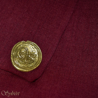 A maroon cashmere Rivella Morven Scarf from Sylvért's Rivanor Collection, folded to show the diamond weave texture and the gold Sylvért stamp