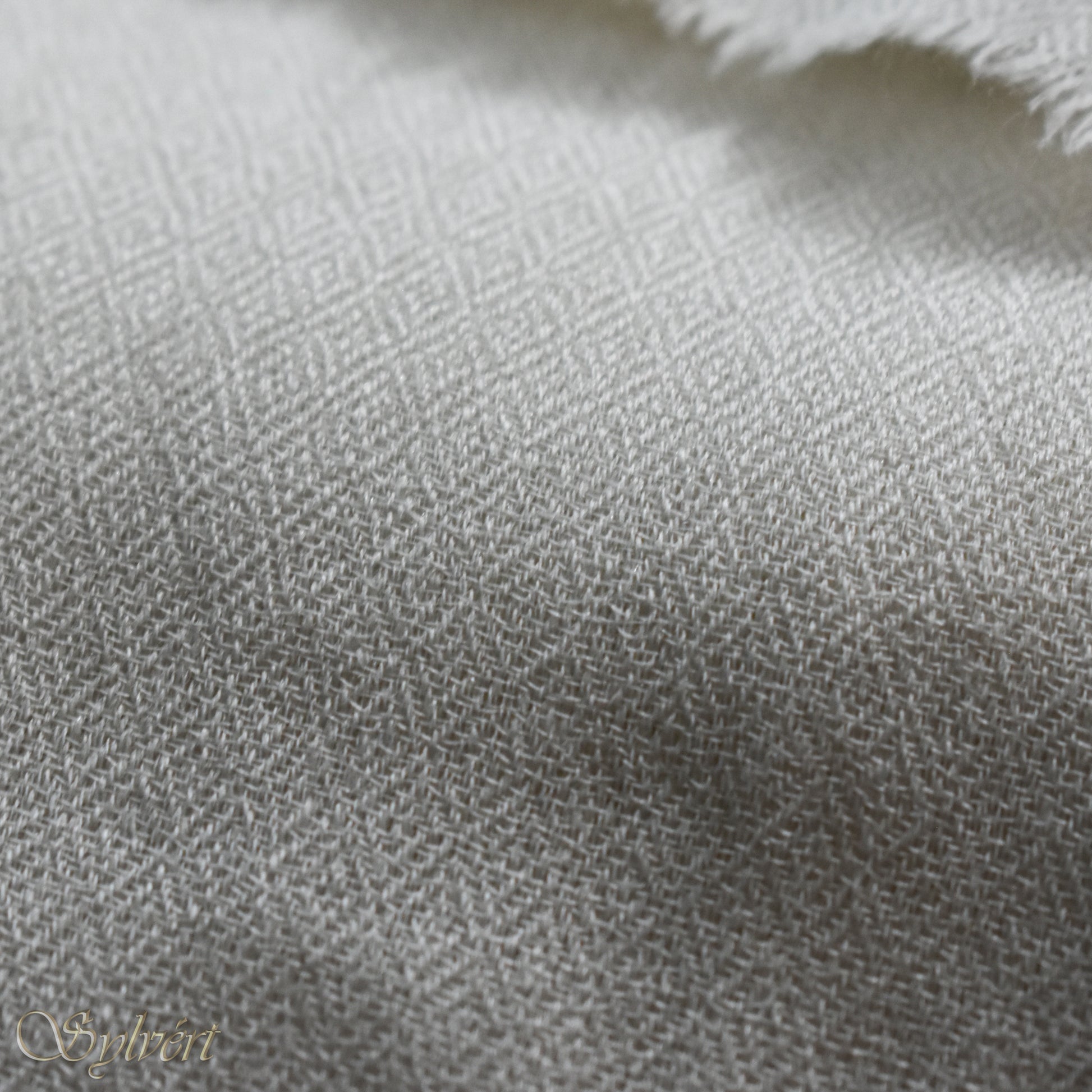 A white cashmere Rivella Caelis Scarf from Sylvért's Rivanor Collection, folded to show the diamond weave texture 