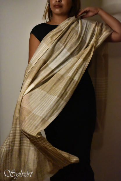 Woman in black dress draping a beige and brown striped shawl indoors