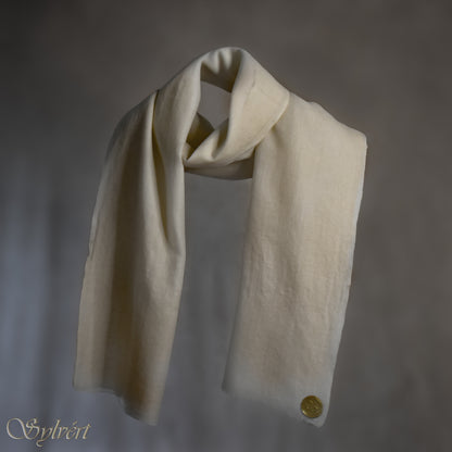 A white Corvella Orlien from Sylvért's Coronis collection, wrapped around itself, suspend in the air behind a beige background, displaying the gold Sylvért stamp
