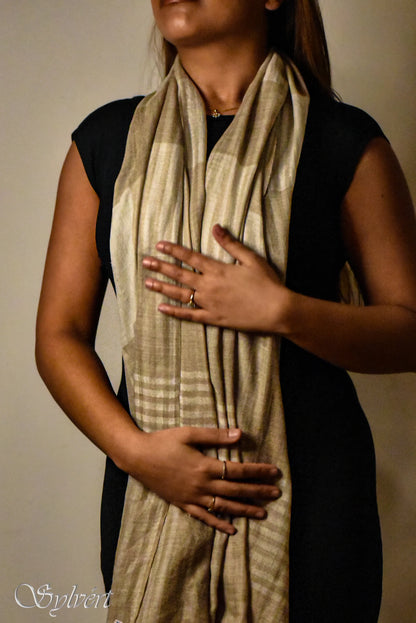 Woman wearing a beige striped scarf over a black dress, showcasing rings on her fingers