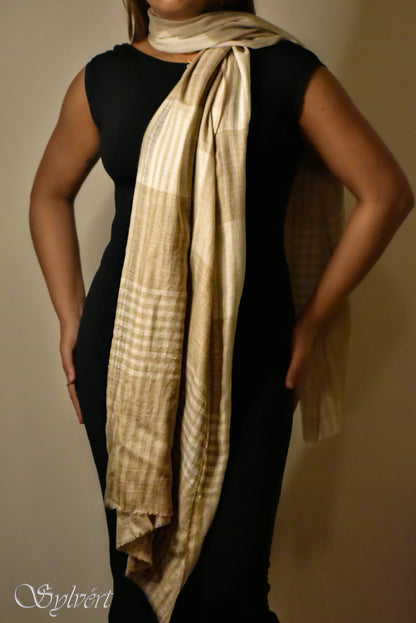 Woman in black dress modeling a beige checkered scarf tied around the neck against a plain background