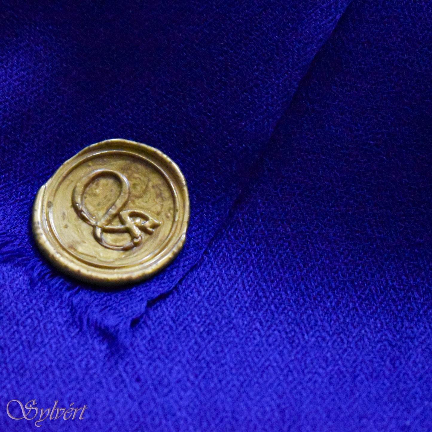 A blue cashmere Rivella Orven Scarf from Sylvért's Rivanor Collection, folded to show the diamond weave texture and the gold Sylvért stamp