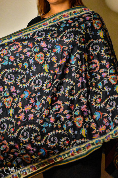 Woman wearing black shawl with colorful floral embroidery and intricate patterns