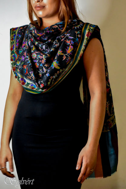 Woman wearing black dress and colorful floral embroidered shawl with green and gold border