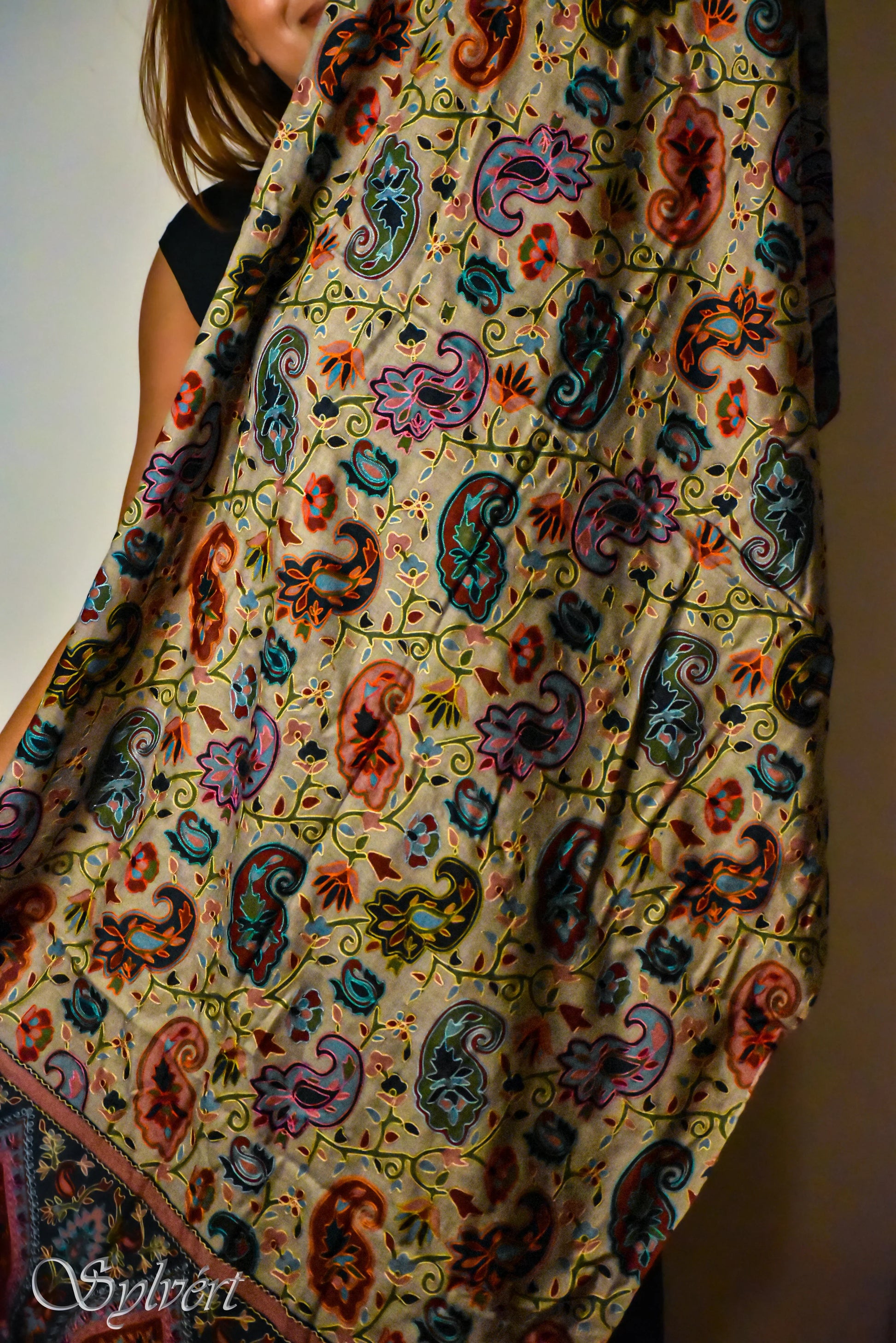 Woman holding colorful paisley patterned fabric with floral and vine details