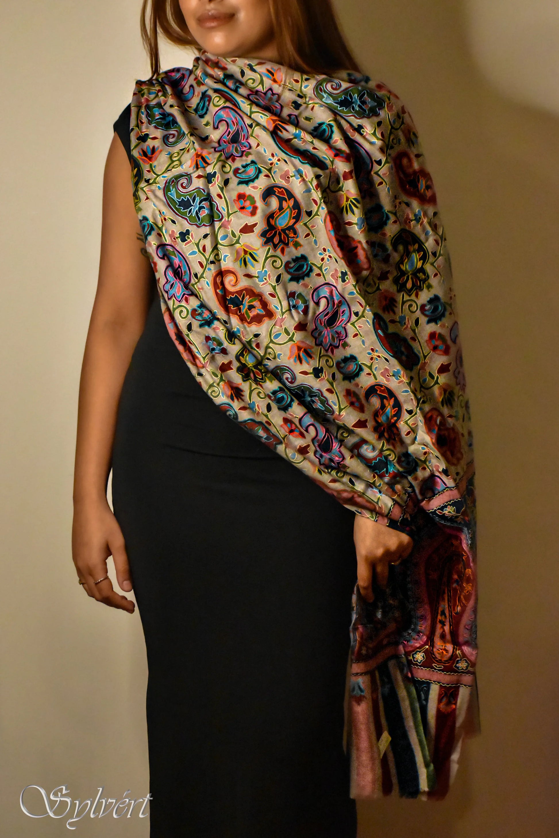Woman in black dress wearing colorful paisley pattern shawl with fringe