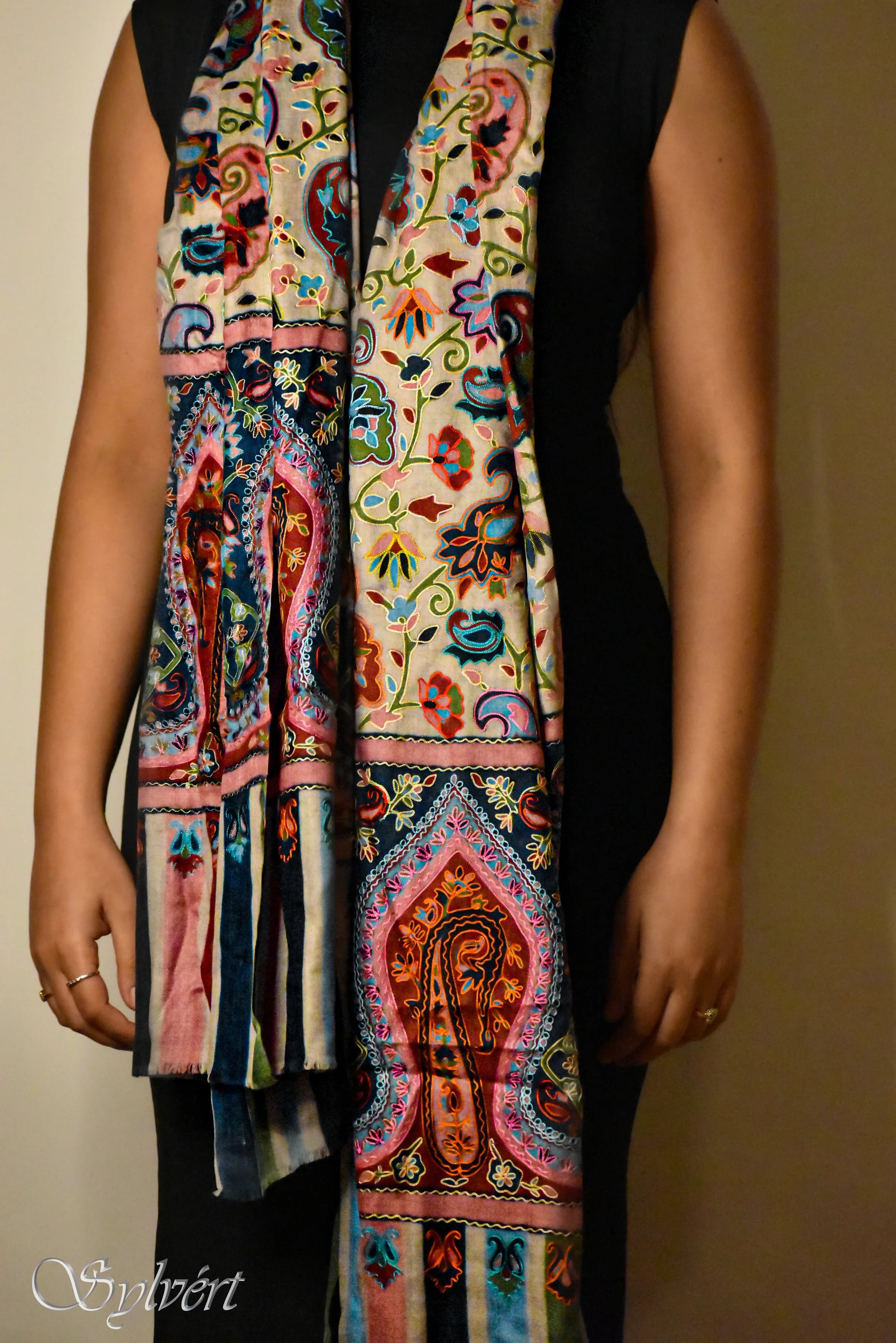 Woman wearing colorful embroidered silk scarf with floral and paisley patterns over black dress