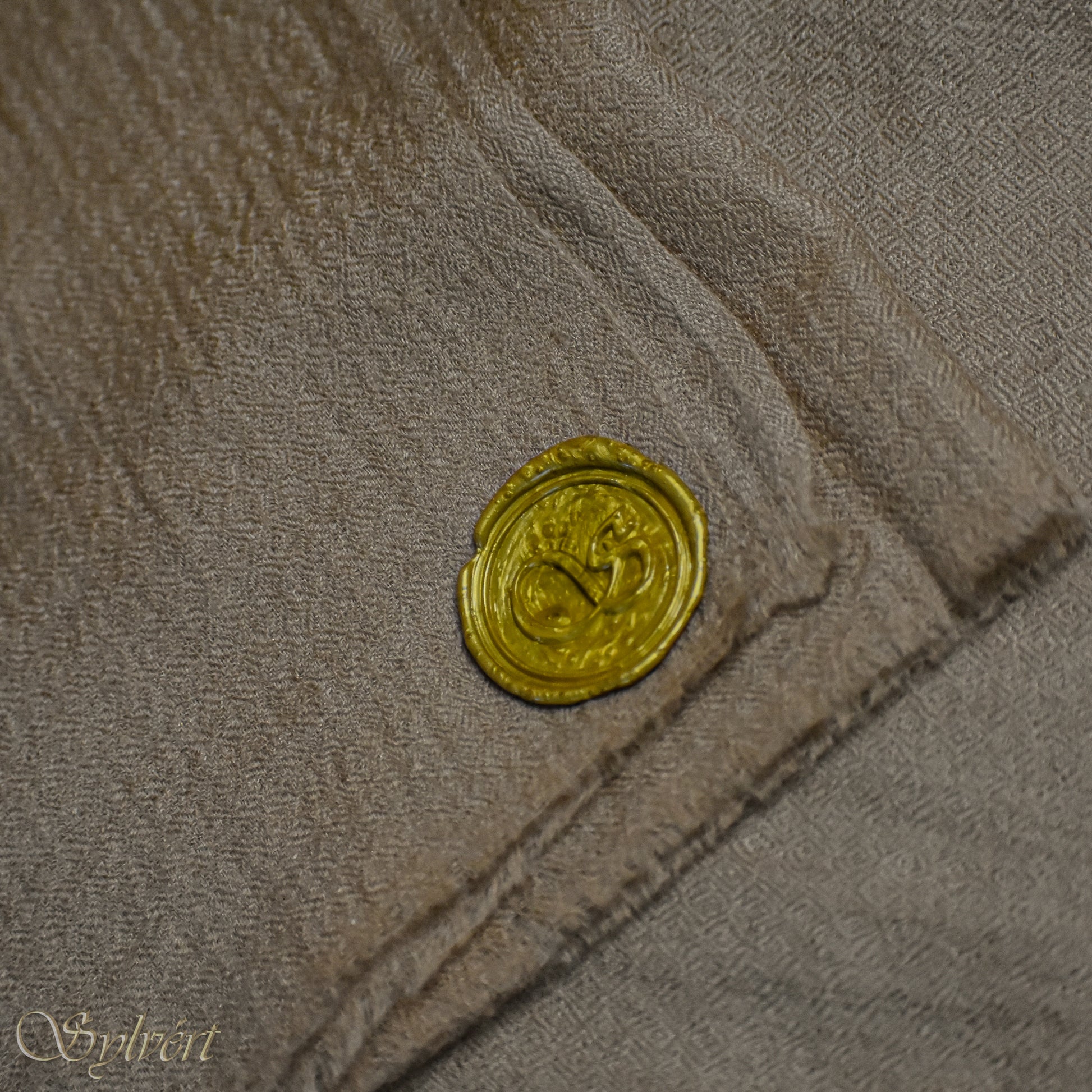 A beige Corvella Draván from Sylvért's Coronis collection, folded to show the diamond weave texture  and gold Sylvért stamp