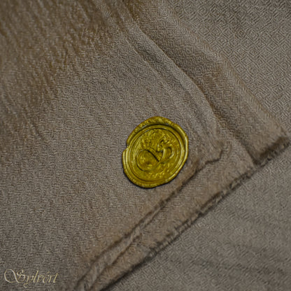 A beige Corvella Draván from Sylvért's Coronis collection, folded to show the diamond weave texture  and gold Sylvért stamp