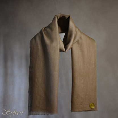 A beige Corvella Draván from Sylvért's Coronis collection, wrapped around itself, suspend in the air behind a beige background, displaying the gold Sylvért stamp